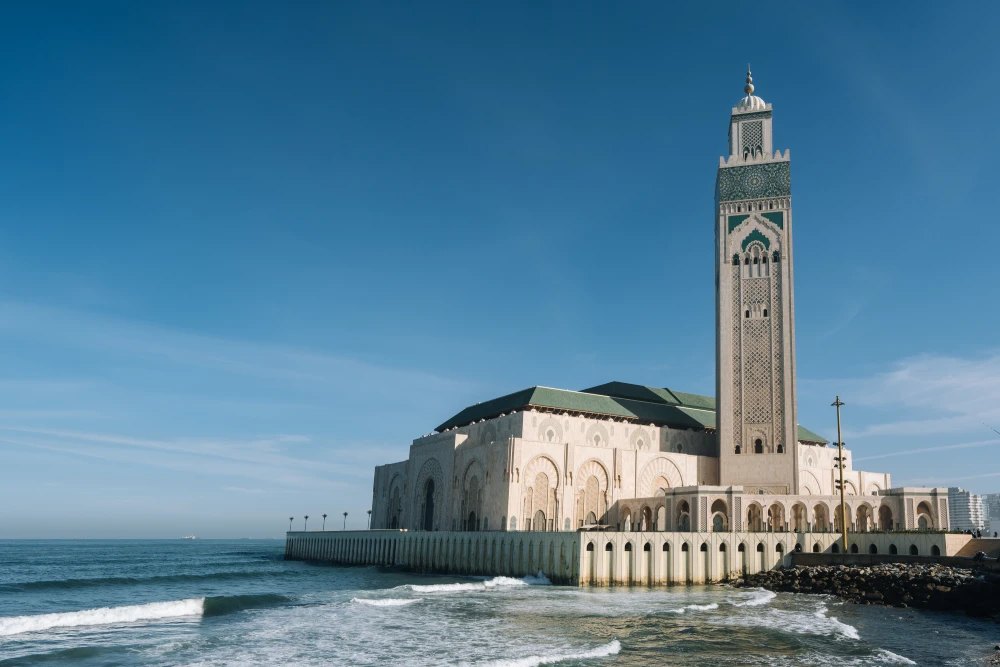hassan ii mosque surrounded by water buildings blue sky sunlight